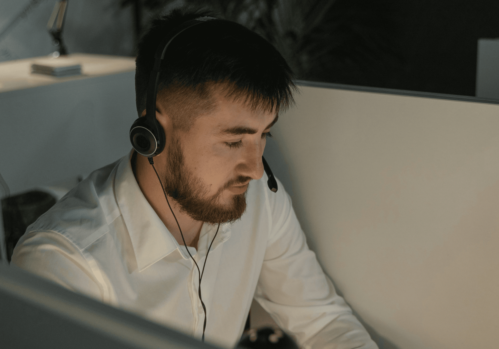 Symbolbild für „Was ist ein Closer“: Ein Mann mit Headset in weißem Hemd  arbeitet konzentriert in einer Telefonkabine